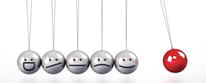 A Newton’s cradle of six balls, five silver with simple emoticon faces and one red ball pulled back on the right against a white background.