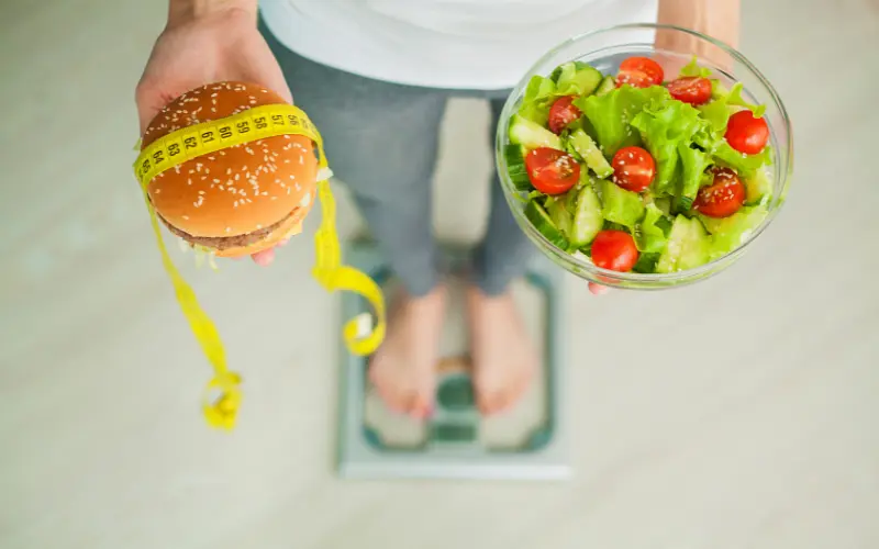 woman choosing between burger and veggies 