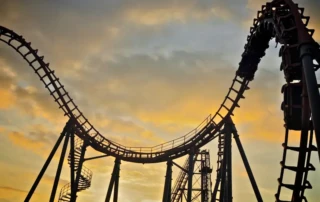 Silhouette of a rollercoaster at sunset symbolising emotional ups and downs in fitness journeys – blog by 5th Element Wellness Fitzroy