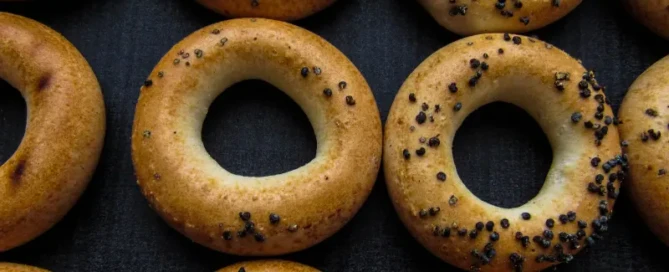 Top view of ring-shaped baked goods with poppy seeds representing refined carbs for 5th Element Wellness blog on carbohydrate quality
