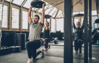 Group of people lifting weights in a gym, guided by coaches — illustrating effective training using Reps in Reserve (RIR) method