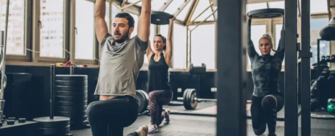 Group of people lifting weights in a gym, guided by coaches — illustrating effective training using Reps in Reserve (RIR) method