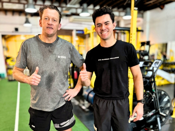 Client and trainer smiling after a training session on the gym floor at 5th Element Wellness in Fitzroy North.