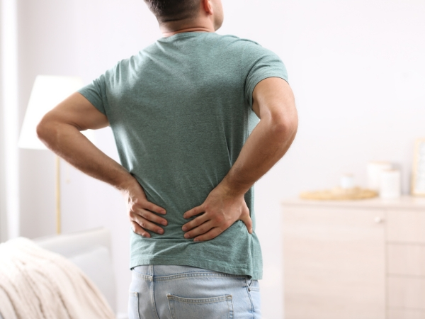 Most Back Pain Comes From Imbalances Back pain personal training at 5th Element Wellness in Fitzroy North, showing a man holding his lower back to represent posture and muscle imbalance–related discomfort.