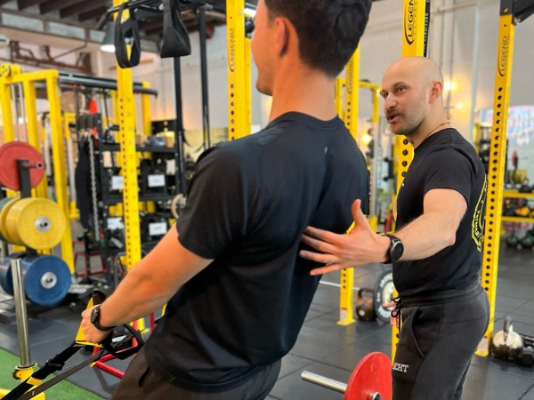 Why Massages, Quick Fixes and Generic Gyms Don’t Work Strength training for back pain at 5th Element Wellness in Fitzroy North, with a personal trainer guiding a client through a controlled back exercise to improve spinal support.