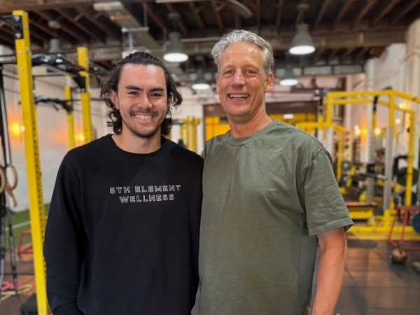 Personal training for busy professionals at 5th Element Wellness in Fitzroy North, showing a client and personal trainer smiling together in a calm, supportive studio.