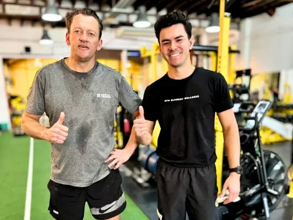 Client and trainer smiling after a training session on the gym floor at 5th Element Wellness in Fitzroy North.