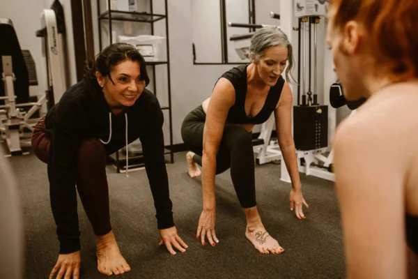 Women performing floor exercises during personal training session in gym