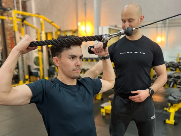 One-on-One Personal Training at 5th Element Wellness Fitzroy North Personal training at 5th Element Wellness in Fitzroy North with coach assisting cable exercise form.