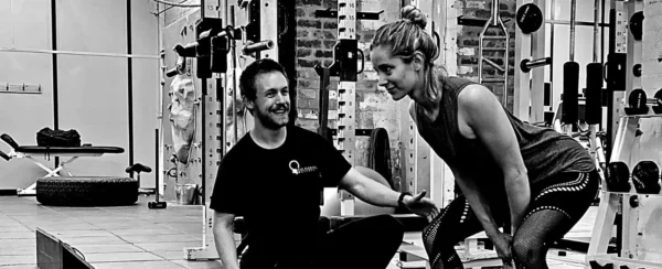 Personal trainer working with female client in gym doing fitness training session