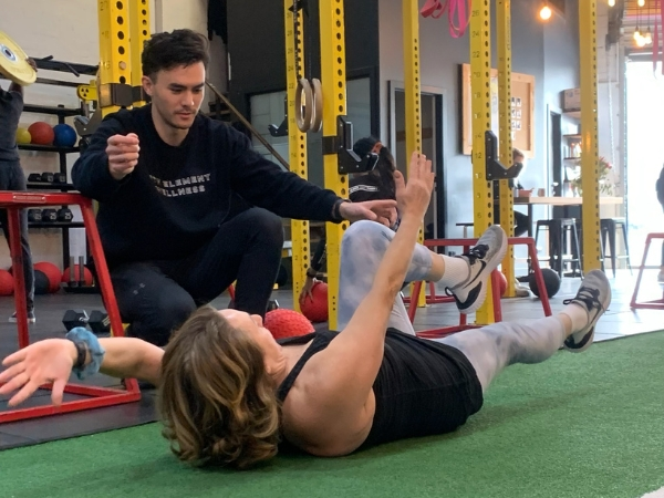 Personal trainer coaching a client through a core stability exercise at 5th Element Wellness in Fitzroy North